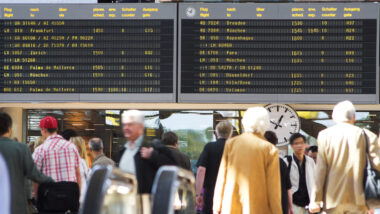 traveler in a train station with an arrivals board in the background
